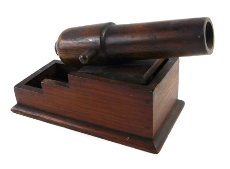 A late 19th/early 20thC oak novelty inkwell in the form of a cannon, the hinged lid enclosing a glass well, 18cm wide.