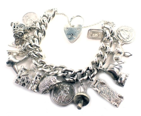 A white metal charm bracelet, with heavy curb link bracelet, safety chain and heart shaped padlock and various drops, to include mushroom, hedgehog, car, donkey, coin, etc., stamped 925, 18cm long, 108.4g all in.