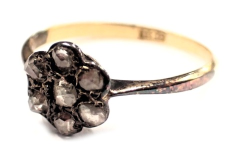 A diamond cluster ring, the floral cluster set with seven old cut diamonds, in a raised basket claw setting, on a yellow metal band marked 18ct, ring size N½, 1.6g all in, boxed.