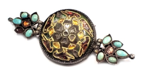 A 19thC and later armlet converted to brooch, possibly late Mughal/Uttar Pradesh, with later additions, the circular moonstone type design with a raised orange and red amber sections and turquoise, in a white metal frame unmarked, on single pin back, 10cm