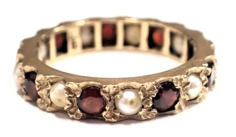 A garnet and seed pearl eternity ring, of hammered claw design, yellow metal unmarked, ring size N½, 3.1g all in.