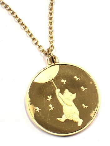 A Winnie the Pooh A. A. Milne pendant and chain, by John Pinches of London, the circular pendant depicting Winnie the Pooh in flight with bees, inscribed 'Because It's Yours, Because We Love You', silver gilt pendant and chain, pendant 2.5cm wide, chain 4