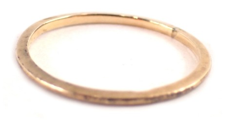 A flattened 9ct gold wedding band, 0.7g. (AF)