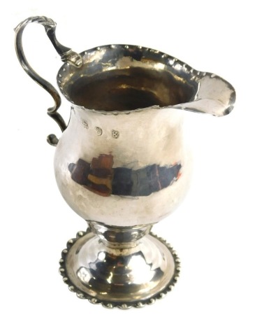 A George IV silver helmet shaped cream jug, with beaded borders, a domed foot and a scroll handle with leaf cast thumbpiece, London 1822, 2.17oz.