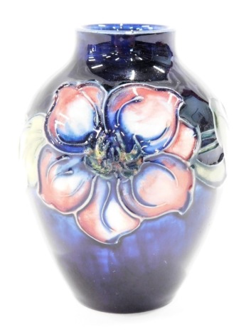 A Moorcroft small clematis pattern bud vase, decorated with pink flower, on a blue ground, with blue stamp to underside, 10cm high.