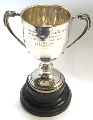 A George VI silver trophy cup, with swag reeded handles, engraved replica, Cooperative Wholesale Society Ltd, National Bakery Exhibition, Silver Championship Cup for Bread, awarded to JA Clayton 1937, Chester 1936, 24cm high, 10.44oz, on ebonised socle.