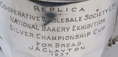 A George VI silver trophy cup, with swag reeded handles, engraved replica, Cooperative Wholesale Society Ltd, National Bakery Exhibition, Silver Championship Cup for Bread, awarded to JA Clayton 1937, Chester 1936, 24cm high, 10.44oz, on ebonised socle. - 3