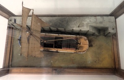 A scale model of a single masted barge, polychrome decorated with realistic base, in stained pine and perspex case, 67cm wide. - 2