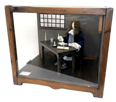 A diorama model of Samuel Pepys, 1633-1703 seated at his desk writing, in wood and perspex case, 61cm wide.