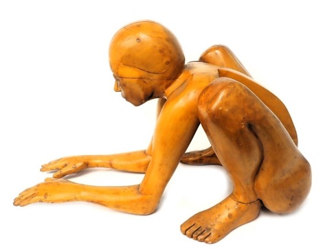 A wooden sculpture of a stylised crouching human, with arms partially resting on the floor, etc., 87cm long.