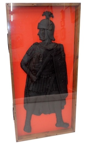 A replica ebonised plaque, modelled in the form of a Roman soldier, in perspex glazed case, 122cm high, 61cm wide overall.