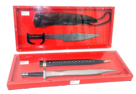 A replica Greek Spartan sword with scabbard, and a Greek sword, both in perspex and red painted wooden cases. (2)