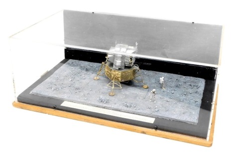 A diorama model of the Apollo Lunar Module Eagle, mounted on a stylised base with astronauts, etc., in perspex and wood case, 36cm wide.