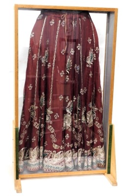 A red silk skirt, embroidered with design of peacocks, in metallic thread, mounted into a floor standing perspex and wooden display case, 108cm high, 64cm wide. - 2