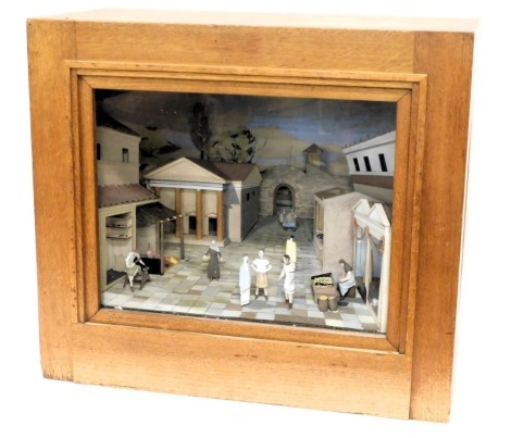 A diorama or model of a Greek or Roman village, polychrome decorated and modelled with people, buildings, etc., in glazed oak case, fitted for electricity, 61cm wide.