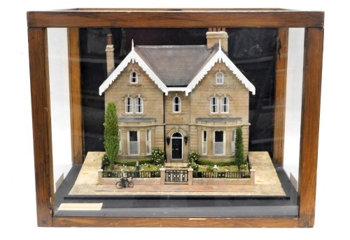 A diorama or model of a Victorian house, from a Victorian house on Regent Square, showing the house, figures with bicycle, etc., in perspex and wooden case, 57cm wide.