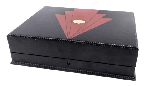 A rectangular storage box, painted in black with applied art deco red detailing, and central plaque opening to reveal two layered interior with beaded border, 12cm high, 40cm wide, and 30cm deep.