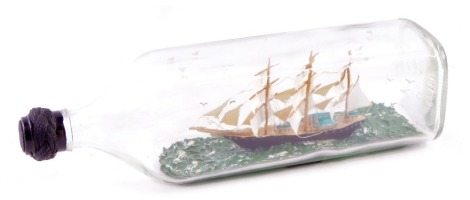 A 1960s/70s painted glass ship in a bottle, 30cm wide.