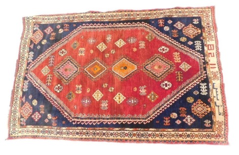 A Persian rug, with a design of multi coloured pole medallion on a red ground with blue spandrels, one wide and two narrow borders, 200cm x 130cm.