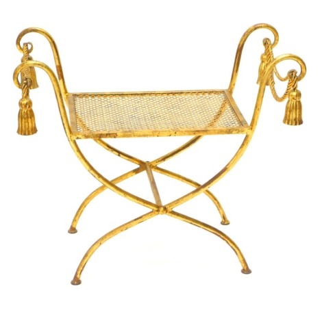 A gilt metal dressing stool, the scroll shaped arms embellished with tassels and rope on X shaped supports.