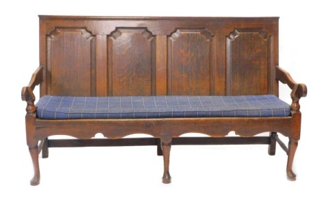 An 18thC oak settle, with a quadruple panel back, shaped arms and a tartan cushion, on cabriole legs with pad feet, 184cm wide.