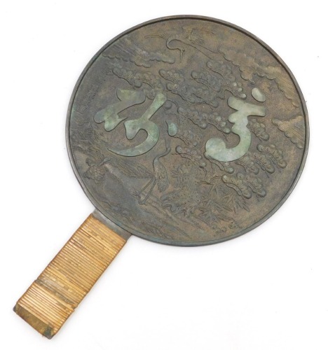 A Meiji period Kagami bronze hand mirror, the reverse embossed with a pine tree and cranes, and two characters, the handle bound in bamboo, signed, 27cm high, 18cm wide.