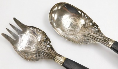 A Malaysian serving fork and spoon set, white metal, chased and pierced with stylised flowers and dragons, with curved horn handles, 21cm long. - 2