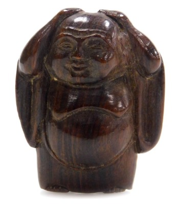 A contemporary Japanese style hardwood netsuke carved as Buddha, in standing pose, with his hands upon his head, 4cm high.