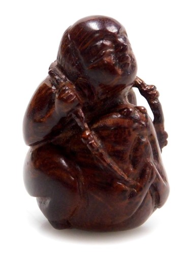 A contemporary Japanese style hardwood netsuke, carved as a boy seated upon a toad, 3.5cm high.