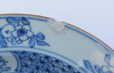 A group of Qing dynasty blue and white porcelain, 18thC and later, comprising a dish decorated with a river landscape, two plates decorated with flowers, and a dish decorated with flowers. (4, AF) - 14