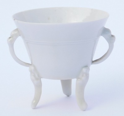 An 18thC Qing dynasty blanc-de-chine porcelain libation cup, of twin handed, tapering form, raised on three mask capped, scroll feet, ex Royal Worcester Porcelain Works Museum label, inventory number 8978, 7cm high. (AF) - 3