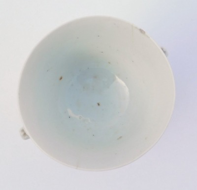 An 18thC Qing dynasty blanc-de-chine porcelain libation cup, of twin handed, tapering form, raised on three mask capped, scroll feet, ex Royal Worcester Porcelain Works Museum label, inventory number 8978, 7cm high. (AF) - 5