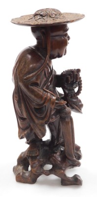 A late 19thC Qing dynasty hardwood carving of a priest, modelled standing, holding a string of beads, and a parasol, with a foliate carved hat, 35cm high. - 4