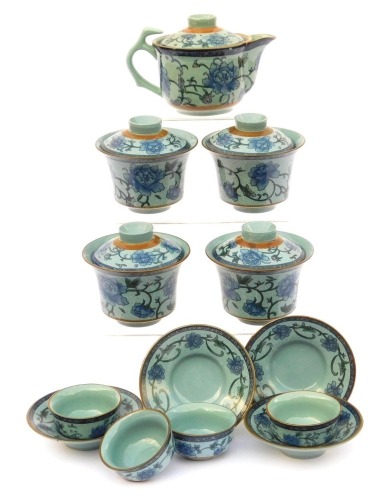 A modern Chinese pottery part tea service, decorated in blue and white with peonies against a pale blue ground, comprising a covered jug, four tea bowls, covers and saucers, and four smaller bowls, together with a metal tea strainer.