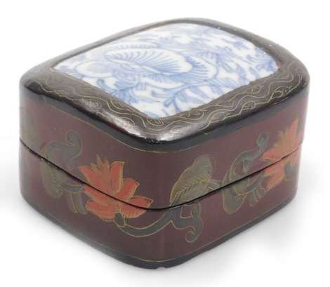 A Chinese red lacquer and porcelain shard box, of rectangular form, with a domed lid, inset with a blue and white floral porcelain shard, the sides decorated with flowers, 9cm wide.