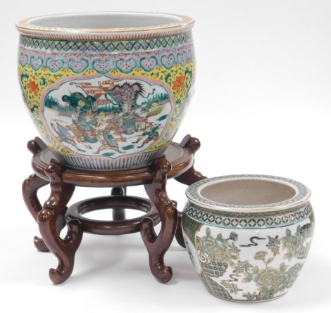 A late 20thC Chinese famille verte porcelain fish bowl, decorated with reserves of warriors, within a yellow ground florally decorated, on a hardwood stand, 46cm high, 31cm wide, together with a famille verte fish bowl, 17cm high, 21cm wide. (2)