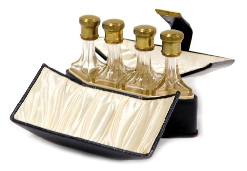 An early 20thC travelling perfume bottle set, comprising four cut glass bottles with gilt metal screw lids, contained in a silk lined purple Moroccan leather case, case 15.5cm wide.