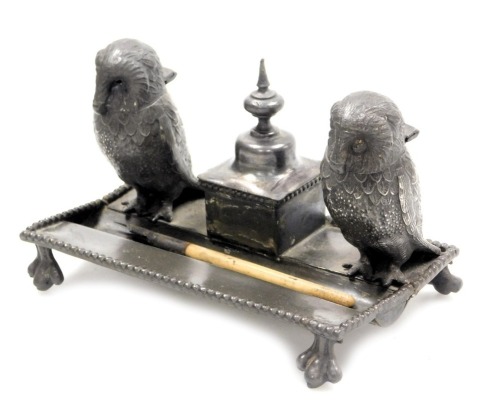 A late 19thC novelty desk stand, with twin owl inkwells and pen recess, on a rectangular base, and four bird's feet, 17.5cm wide.