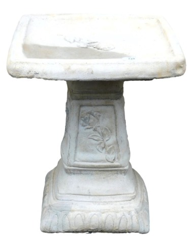 A concrete birdbath, with a square top, raised on a column with floral panels, 48cm high.