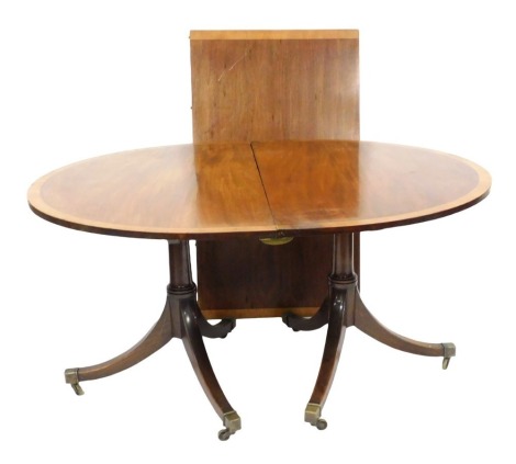 A Georgian style mahogany and yew wood cross banded oval twin pedestal dining table, with one additional leaf, 69.5cm high, 202cm wide, 112cm deep.