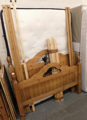 A pine double bed frame, comprising head and foot boards, side rails and a mattress.