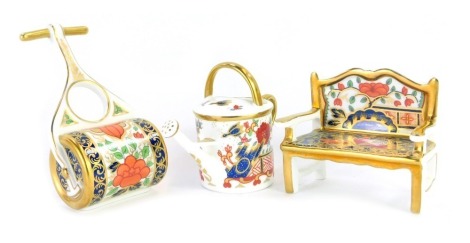 Three pieces of Royal Crown Derby Miniatures Imari porcelain, comprising Pardoe garden bench, 8cm high, Rich Japan watering can, 7cm high and Lotus Blossom garden roller, boxed.