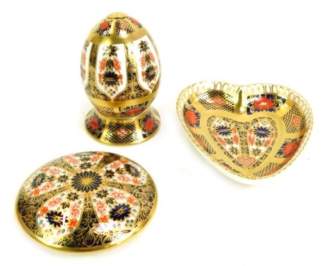 A group of Royal Crown Derby Old Imari porcelain, gold ground, pattern 1128, comprising heart shaped trinket dish, 9cm wide, (AF), a Royal Antoinette domed trinket tray, 8cm diameter, and an egg on stand. (3)