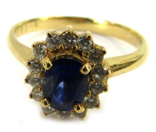 A sapphire and diamond dress ring, set with central oval sapphire approx 0.84ct, in four claw setting, surrounded by halo of tiny diamonds totalling 0.28ct overall, in a raised basket on a yellow metal band stamped 750, ring size P, 4.2g all in.