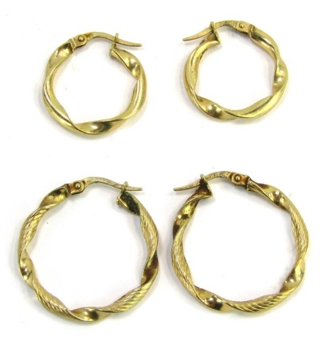 Two pairs of hoop earrings, each yellow metal, stamped 375, comprising a pair of small twist design hoops, 1.5cm wide, and a pair of twist and hammered design hoops, 2.5cm wide, 2.4g all in. (2)