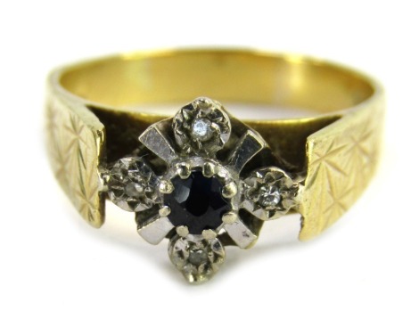 An 18ct gold sapphire and diamond dress ring, the central floral cluster in white metal, with central sapphire flanked by four illusion set tiny diamonds, on a yellow metal band with star design shoulders, ring size O½, 5.1g all in.