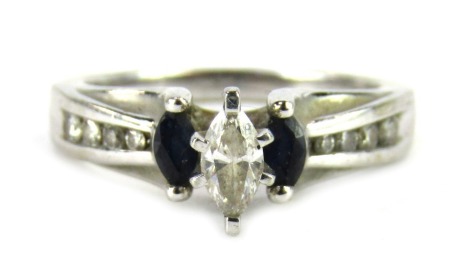 A sapphire and diamond dress ring, the marquise shaped raised central diamond approx 0.08ct, flanked by two marquise shaped sapphires and four tiny diamonds to each shoulder, yellow metal stamped 18k, ring size O, 4.4g all in.