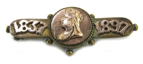 A commemorative bar brooch, dated 1897, with central figure of Queen Victoria, on a brass base frame with raised 9ct gold decoration, single pin back, 4cm wide.