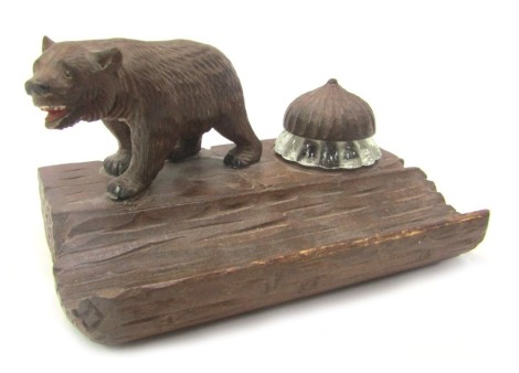 A 20thC Black Forest desk stand, surmounted by a carved bear, beside glass ink well with carved stopper and recess for pens, 15cm wide.