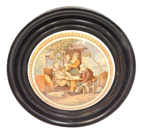 A Victorian Pratt ware pot lid, depicting two figures seated at games table, with dog, mother and child, A.6, in turned ebonised frame, 18cm diameter.